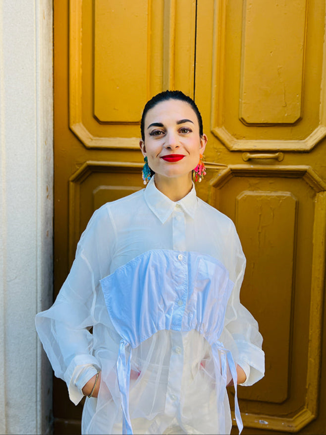 Woman in a white blouse standing in front of a yellow door